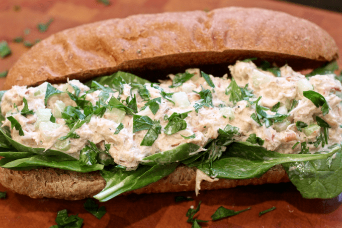 Crab salad sandwich on a whole wheat hoagie roll with parsley and spinach