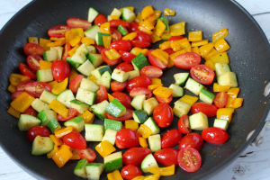 Colorful mixed vegetables being cooked in a large skillet