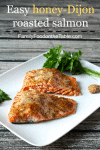 Close up of roasted salmon with a honey mustard topping on a white platter with a small bunch of fresh parsley to the side.