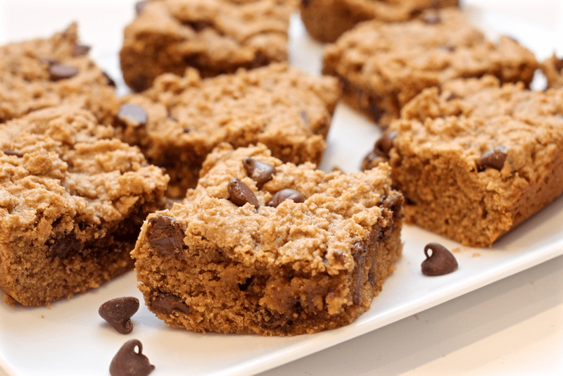 Close up of square peanut butter chocolate chip bars on a white plate.