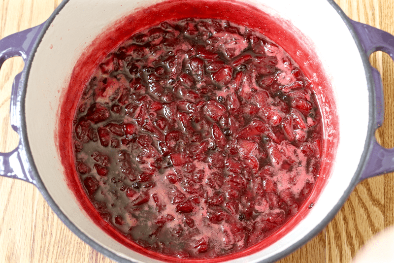 Homemade strawberry jam being made in a large purple pot