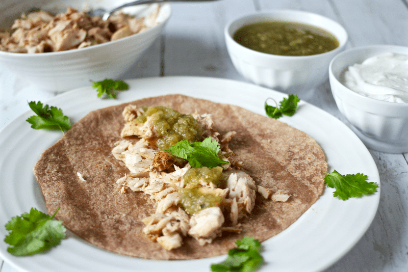 Mahi mahi fish taco on a white plate with salsa verde and cilantro.