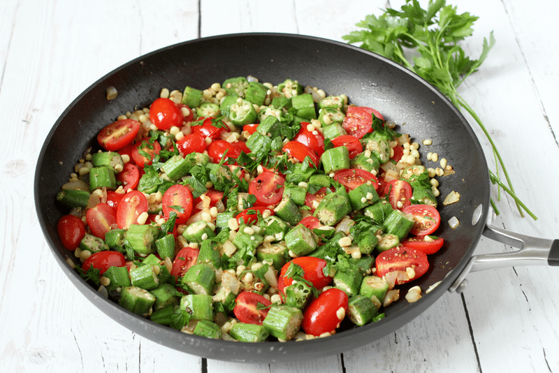 This quick okra, corn and tomato sauté makes the most of fresh summer produce and is ready in under 20 minutes for a delicious veggie side dish! A large dark skillet with sautéed okra, corn and tomatoes