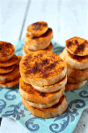 Close up of spicy roasted sweet potato rounds stacked up on a teal plate.