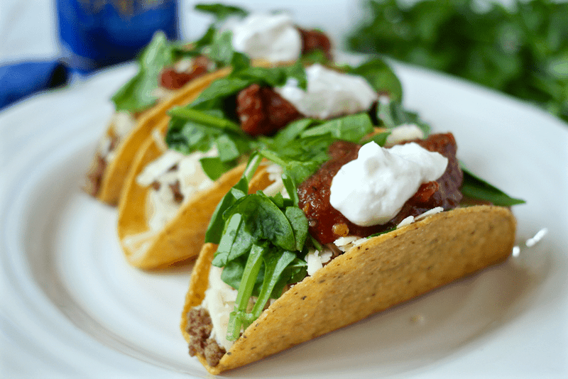 A plate with crispy corn tacos loaded with toppings