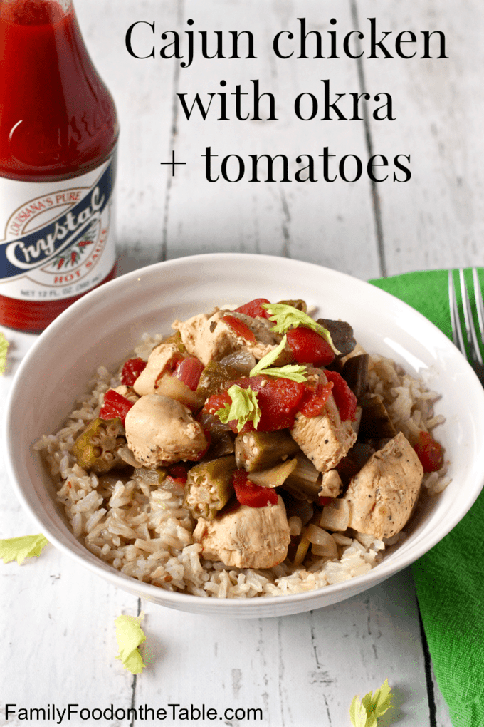 Cajun chicken stew with okra and tomatoes served over rice in a white bowl with a text overlay on the photo.