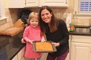 A woman and her young daughter holding a pan of baked pumpkin yogurt cake.