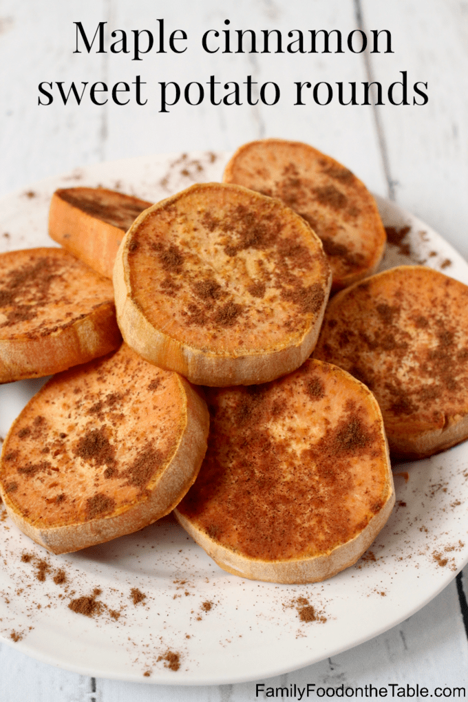 A pile of roasted sweet potato rounds on a white plate with cinnamon sprinkled all over top.