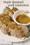 A sliced roasted pork tenderloin arranged on a plate with a maple mustard sauce drizzled on top and in a bowl to the side.