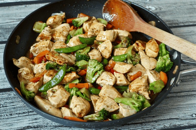 Chicken stir fry with vegetables in a saute pan.