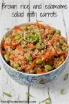 A bowl of brown rice with edamame, carrots and sliced green onions with sesame seeds sprinkled on top.