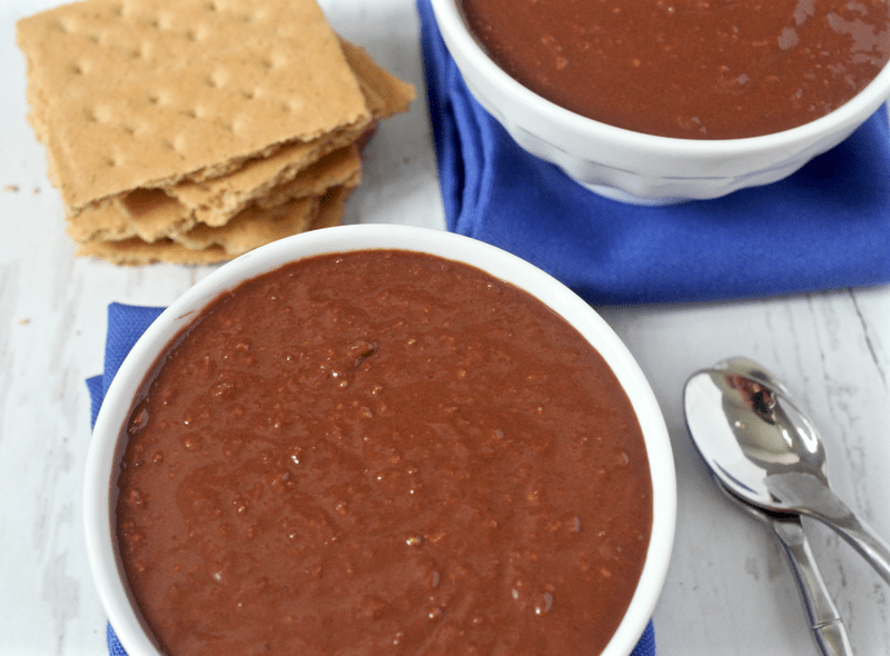 Two bowls of homemade healthy chocolate pudding with a stack of graham crackers to the side.