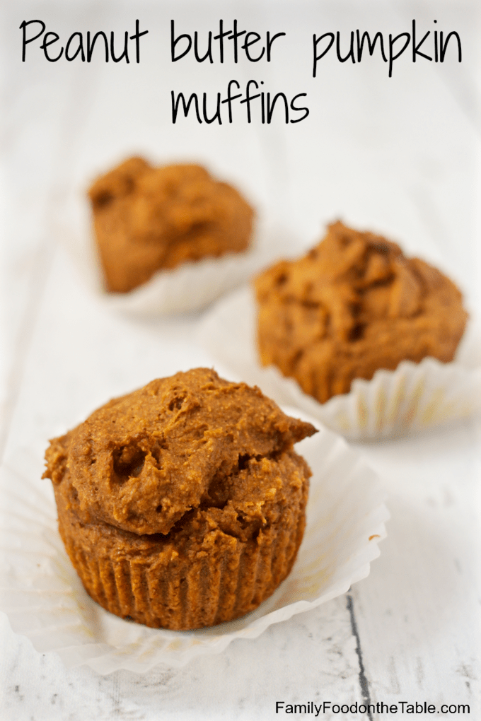 Unwrapped baked pumpkin peanut butter muffins on a counter.