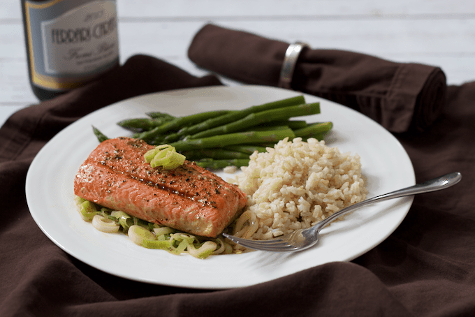 A dinner plate with salmon, rice and asparagus