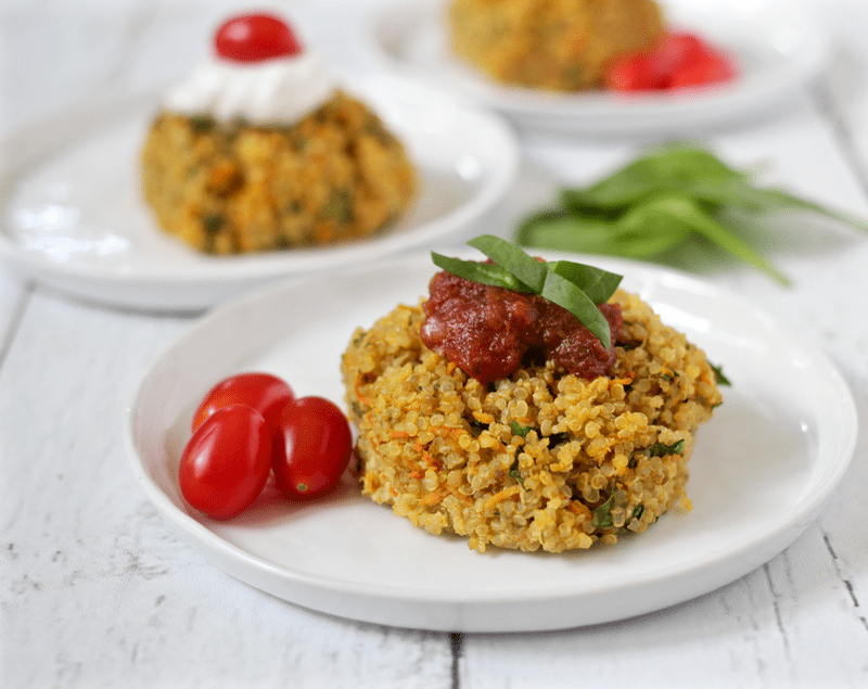 Mini quinoa muffins with veggies on white plates topped with salsa and sour cream.