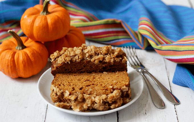 Whole wheat pumpkin applesauce bread slices served on a white plate with pumpkins in the background