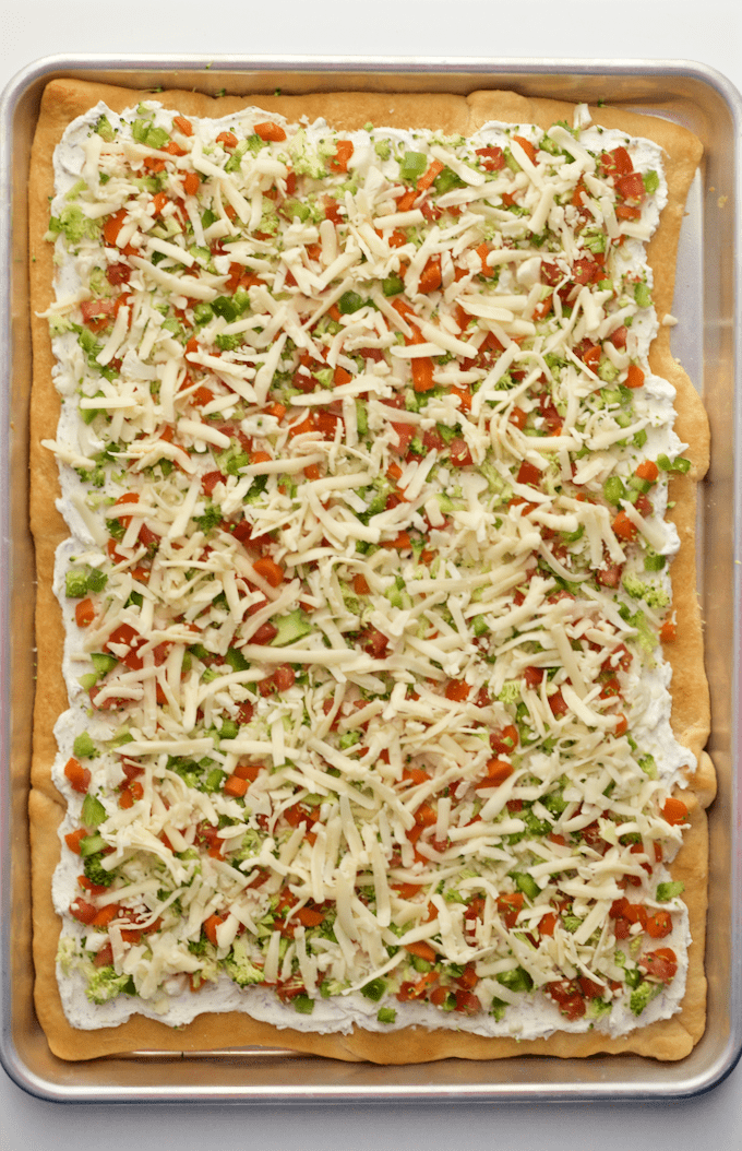 Easy vegetable squares on a large baking sheet covered with chopped veggies and shredded cheese