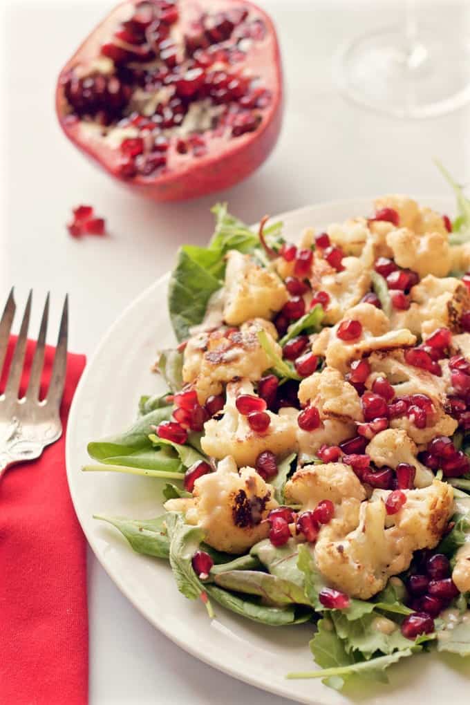 Close up of a salad with baby kale, roasted cauliflower and pomegranate seeds.