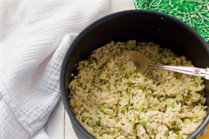 Healthy brown rice recipe with broccoli and cheddar cheese mixed in, being served from a large pot