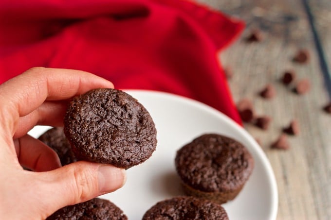 Healthy double chocolate mini cupcakes on a white plate with one picked up