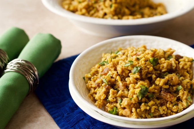 Cold curried rice salad served in a bowl with parsley sprinkled on top