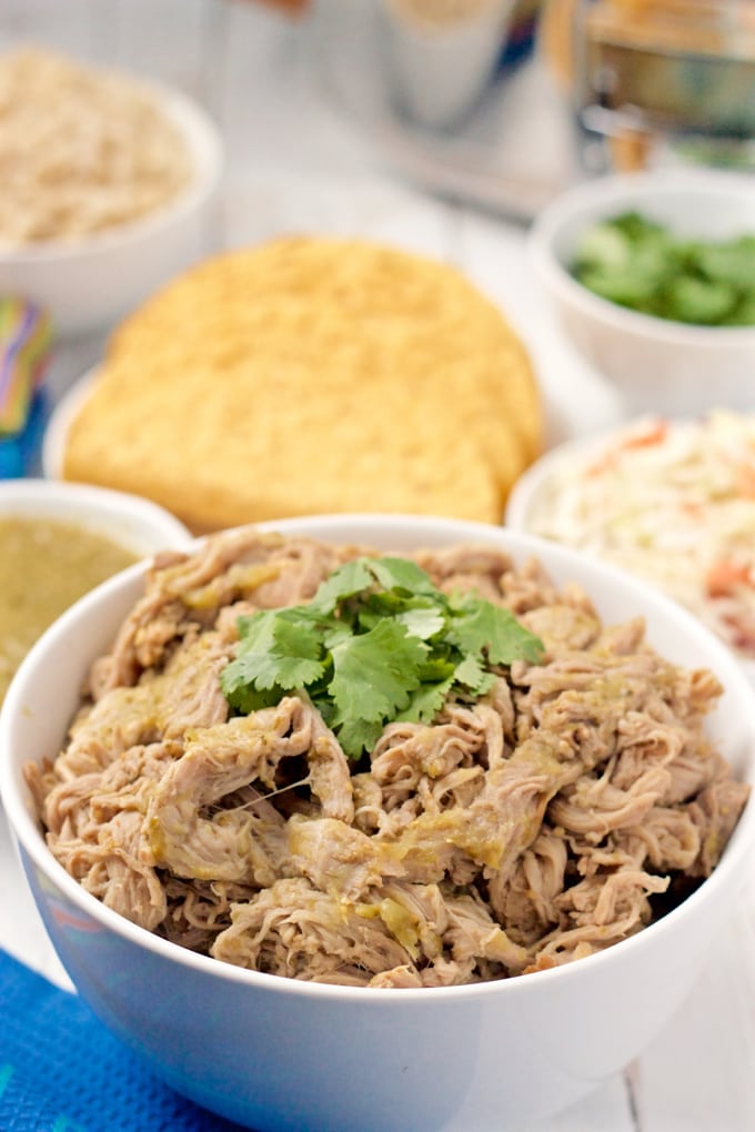 Slow cooker salsa verde shredded pork in a white serving bowl with cilantro on top