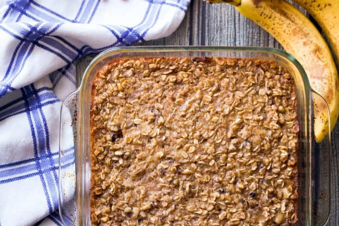 Baked oatmeal in a glass pan with bananas on the counter nearby