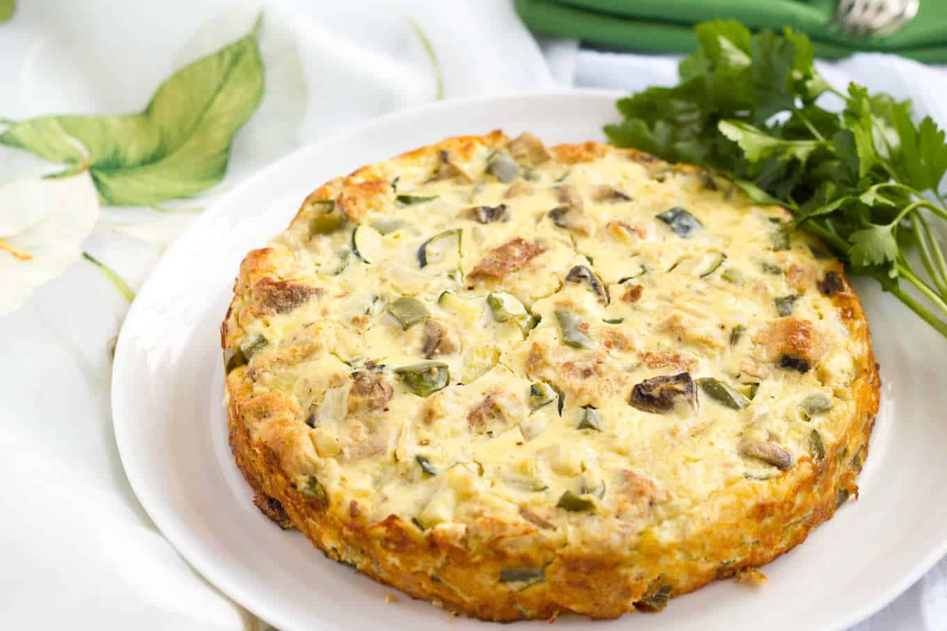 A vegetable frittata served on a large white platter.