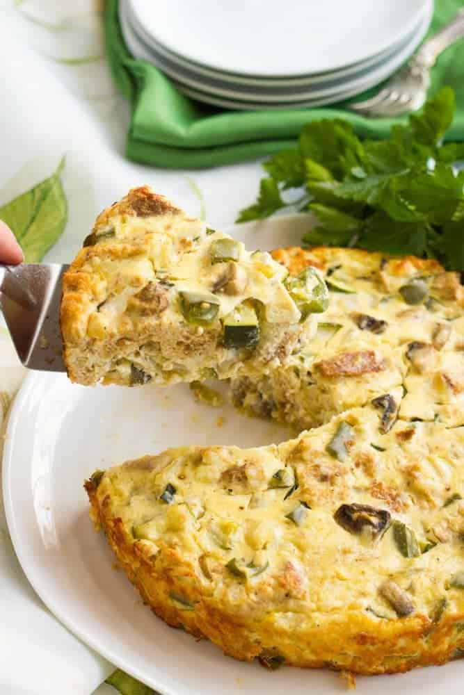 A slice being lifted up from a baked vegetarian frittata