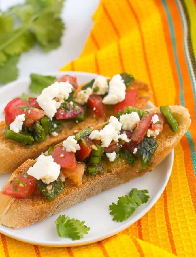 A couple of pieces of Mexican style bruschetta served on a plate