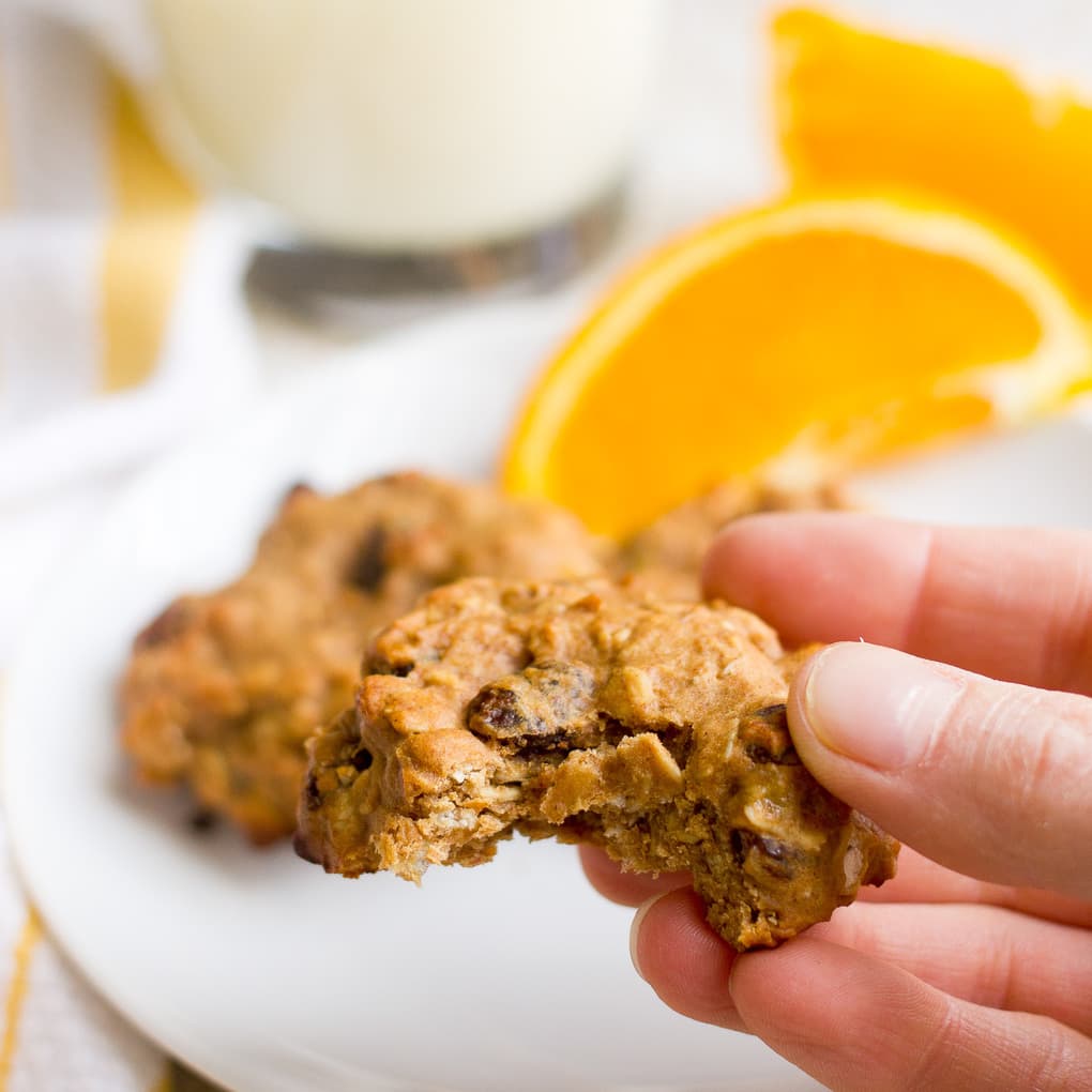 A hand holding a cookie with a bite taken out