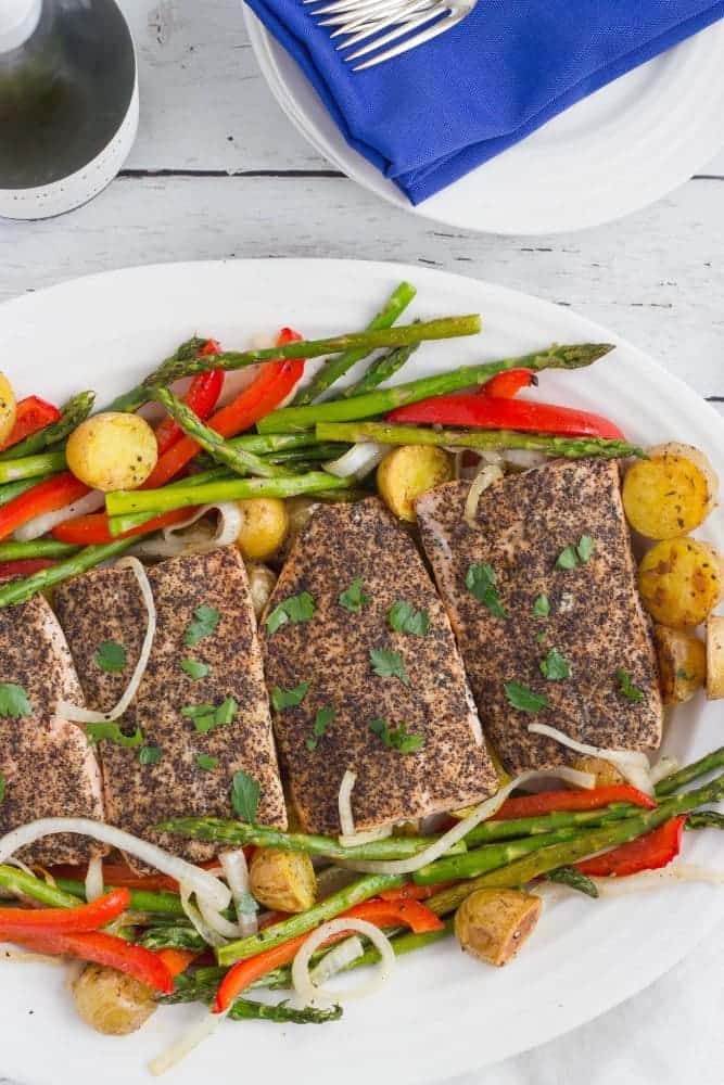 A large white platter of roasted salmon and vegetables 