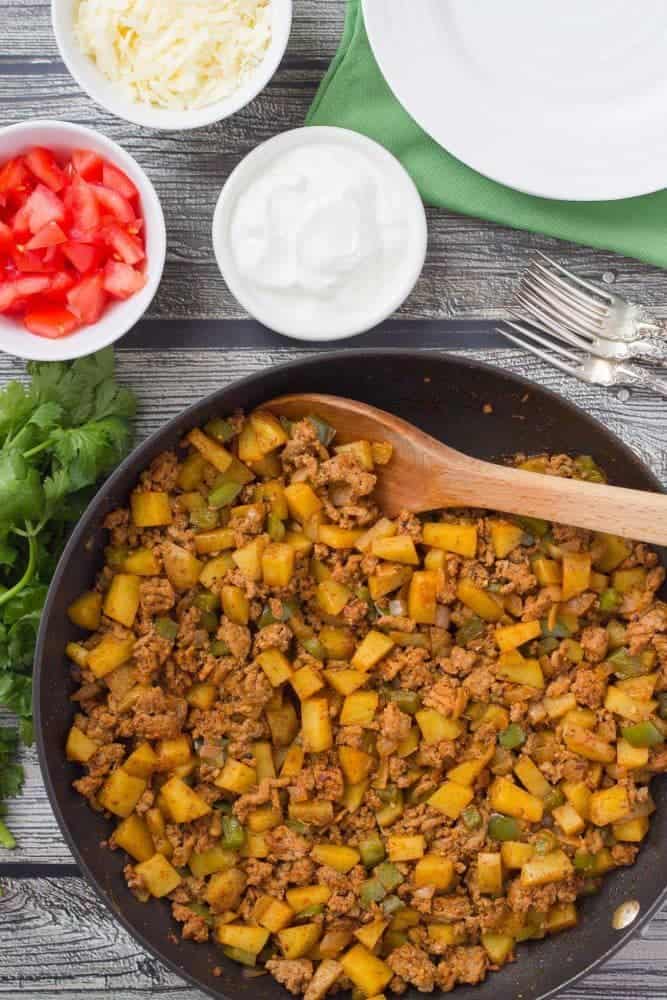 Turkey potato skillet with toppings in bowls nearby