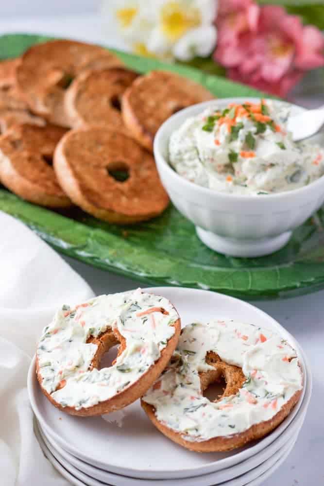 A bagel spread with veggie cream cheese served on a white plate