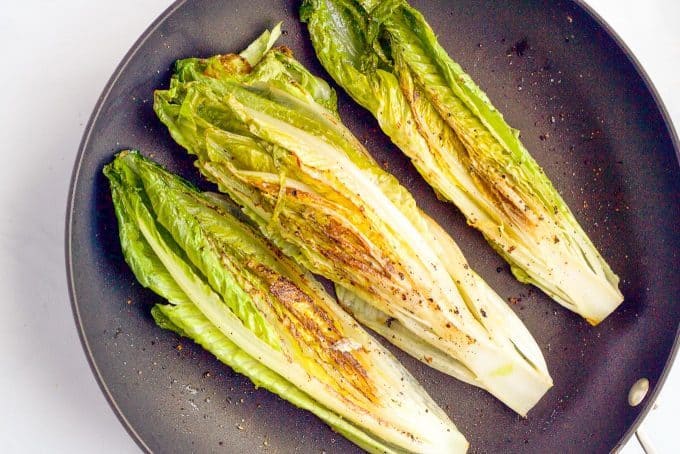 Romaine strips seared in a saute pan with browned spots showing