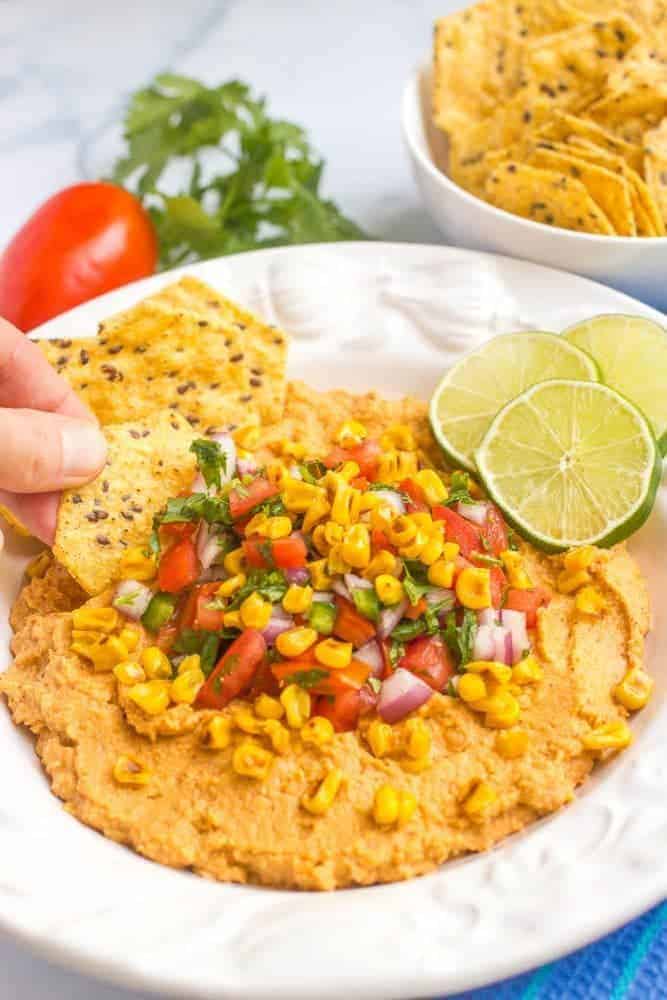 Southwestern hummus dip is topped with an easy, fresh pico de gallo and charred corn for a fun and tasty appetizer! #hummus #salsa #appetizer #gamedayeats #healthysnacks