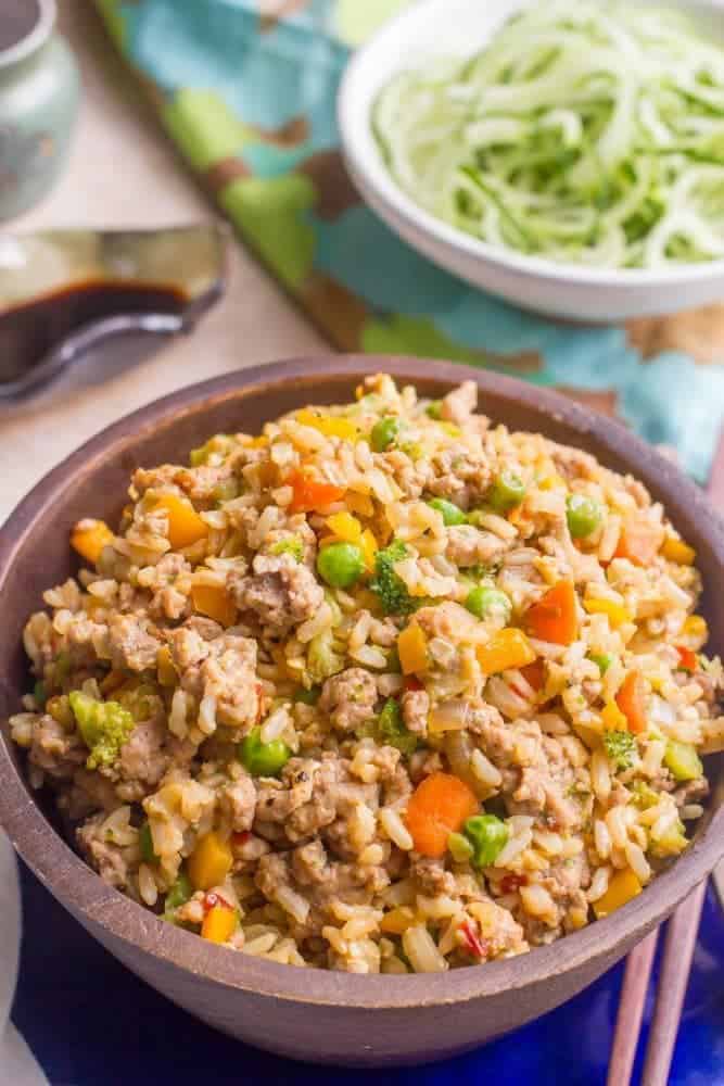 A brown bowl full of fried rice with ground pork and vegetables