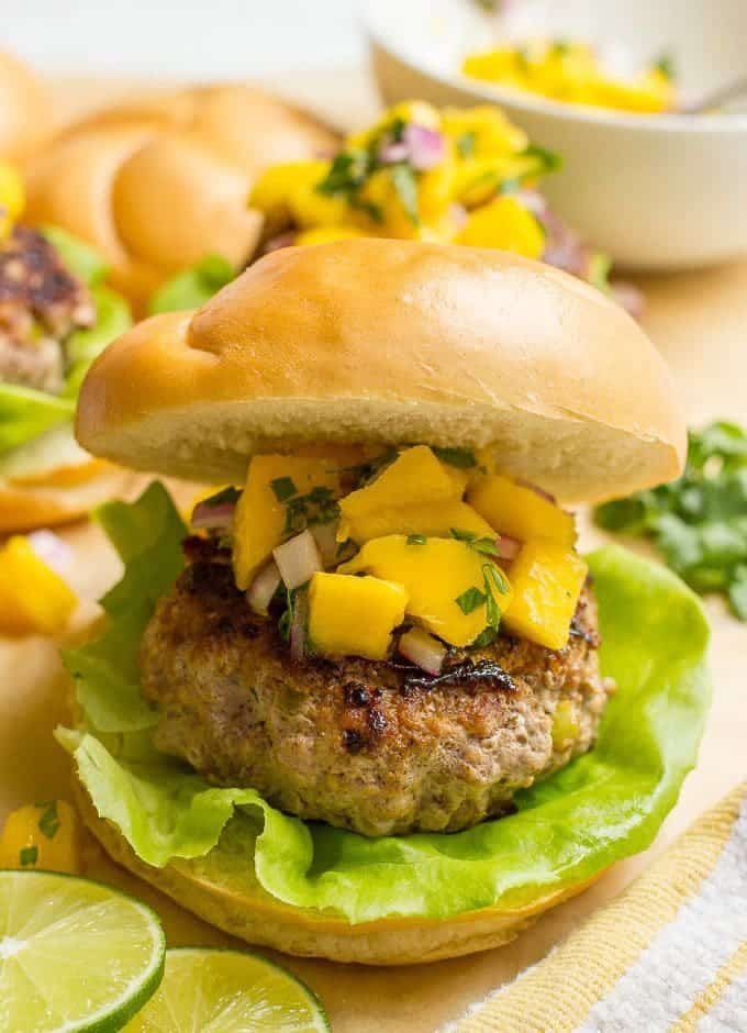 A pork burger topped with mango salsa and served on a hamburger bun