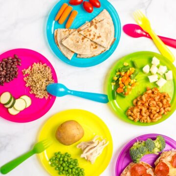 Five colorful plastic kids plates each with a different assortment of an easy, quick meal, including quesadilla, English muffin pizzas, pasta and rice and beans.