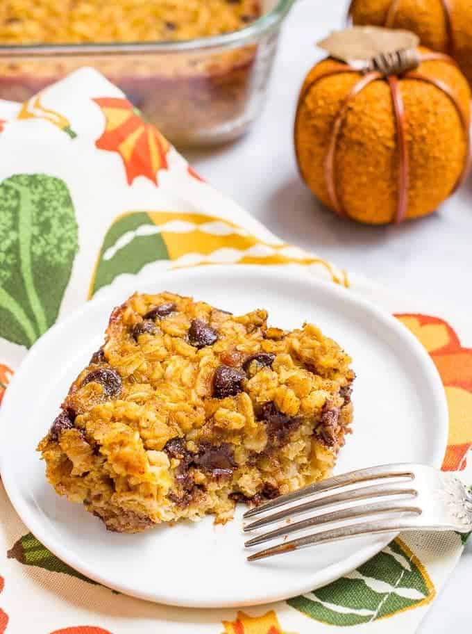 A fork resting on a small white plate with a square piece of a baked oatmeal with a bite taken out of it.