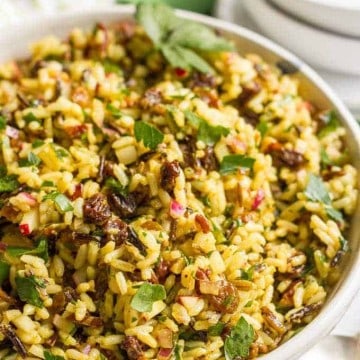 Close up of a wild rice salad mixed with raisins and chopped pecans and radishes in a bowl.