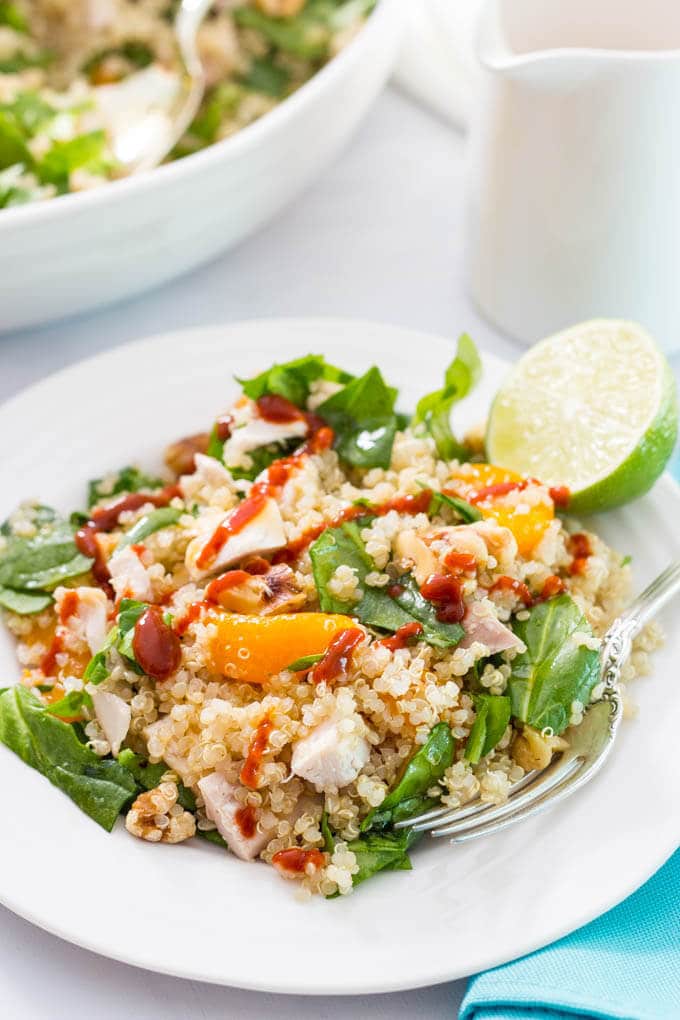 Quinoa chicken spinach salad with mandarin oranges, walnuts, served with a honey-lime vinaigrette and sriracha drizzle! | www.familyfoodonthetable.com