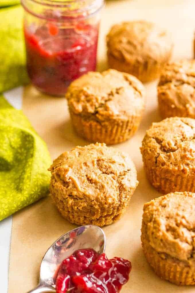 Whole wheat peanut butter muffins on a parchment paper with a spoonful of jelly nearby