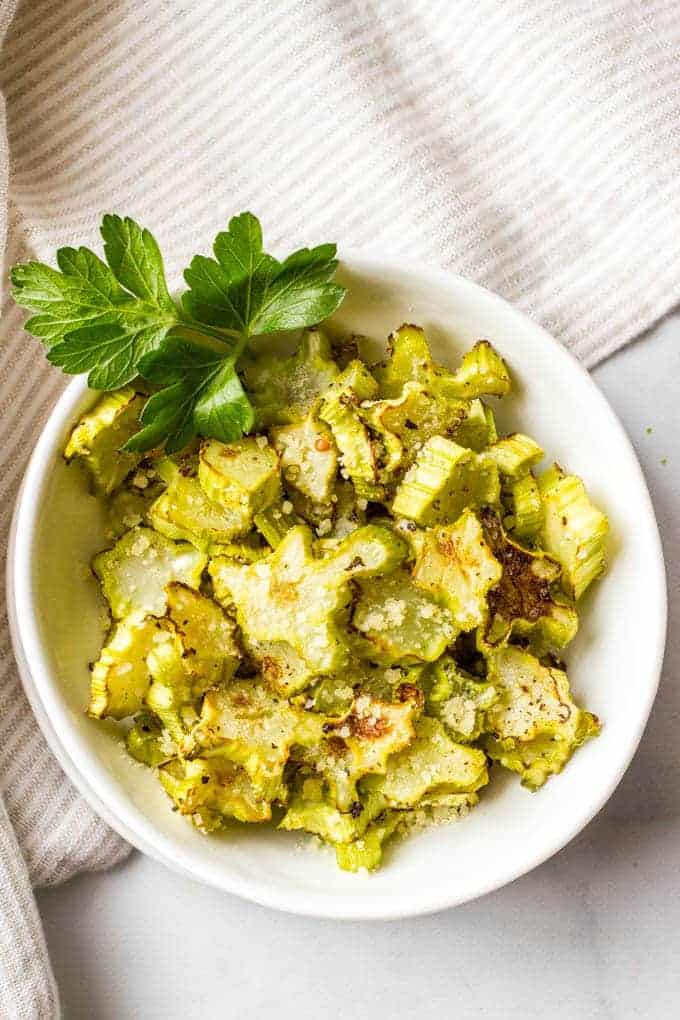 A small white bowl full of roasted broccoli stems topped with Parmesan cheese.