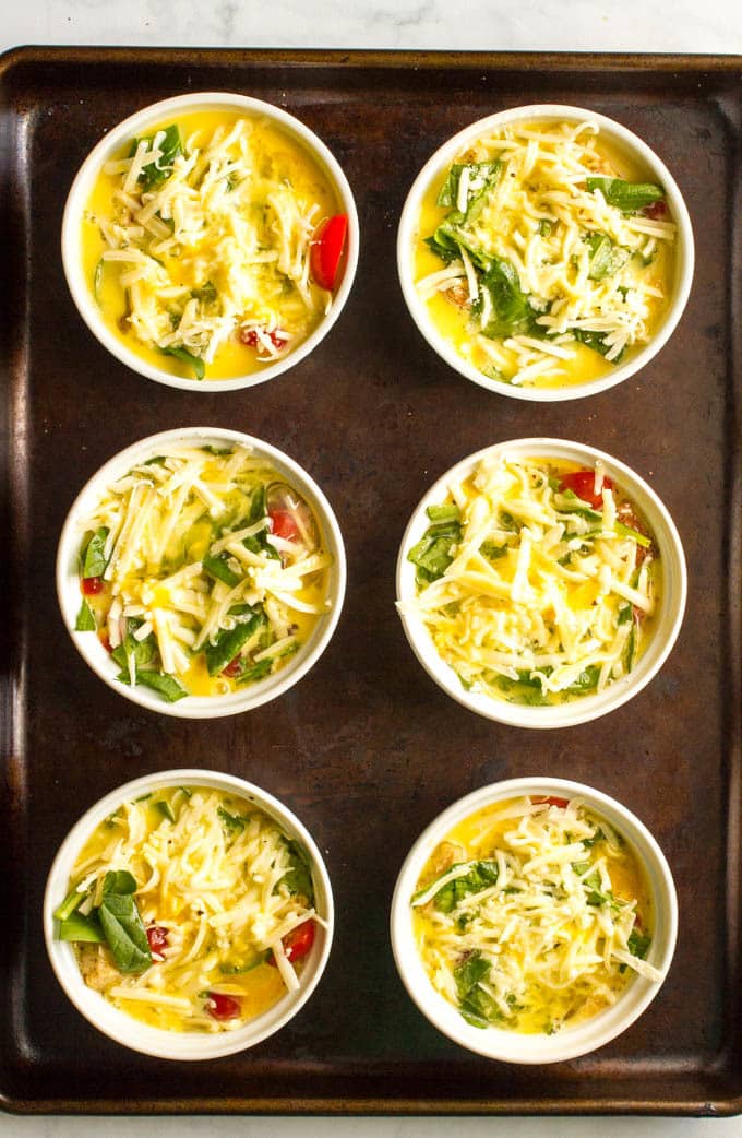 Individual breakfast casseroles in ramekins on a baking tray before being cooked