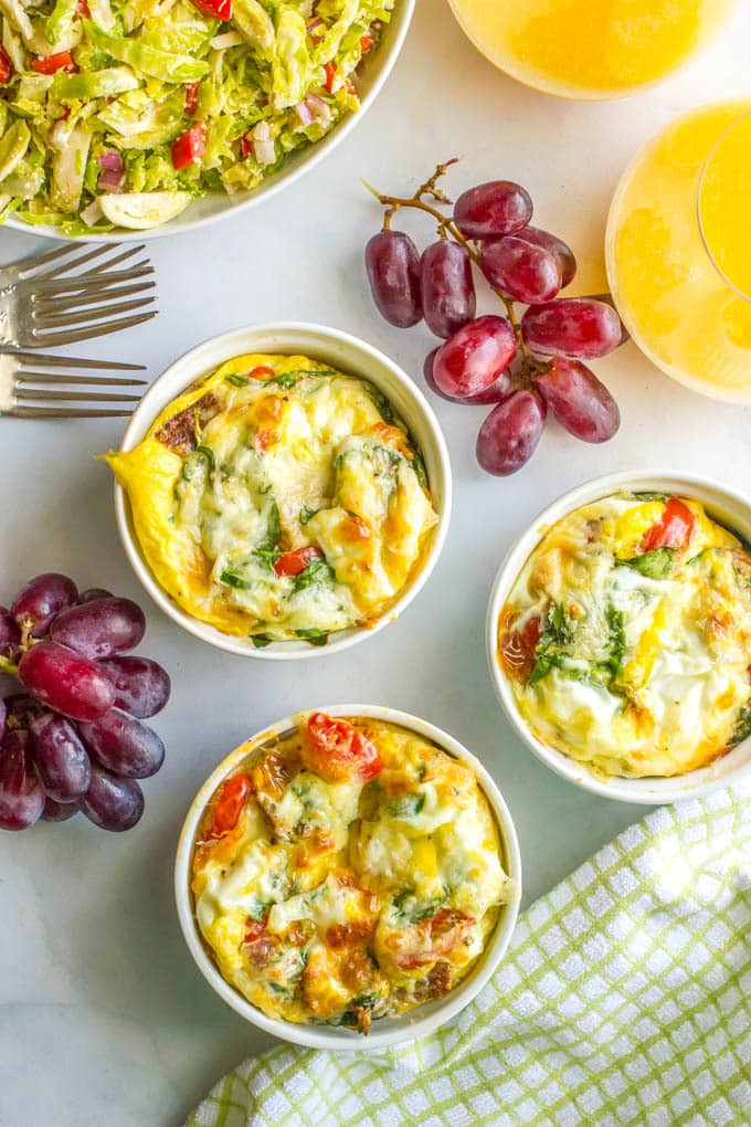 Individual egg breakfast ramekins set out with orange juice and fruit