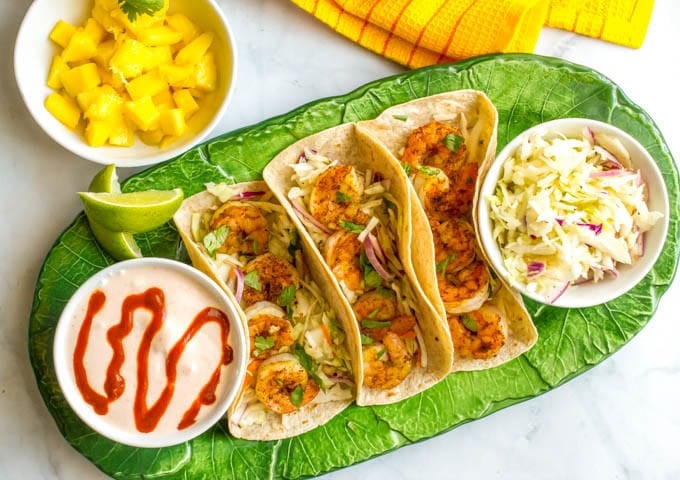 Shrimp tacos with lime cabbage slaw and spicy yogurt sauce make for a quick and easy dinner that’s big on flavor! | www.familyfoodonthetable.com