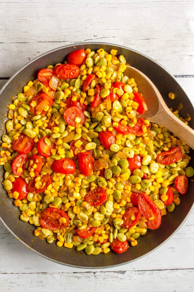 Corn, lima beans and tomatoes cooking in a skillet for summer succotash