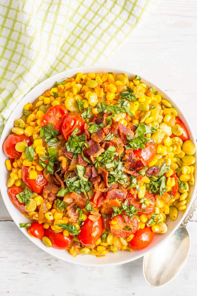 Southern-style succotash in a large bowl with bacon and fresh herbs on top