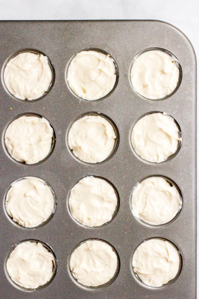 Graham cracker crusts and cheesecake filling in mini muffin tin